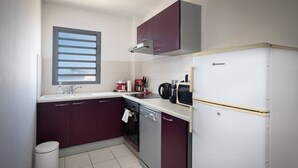 A compact kitchen with a dishwasher, a microwave, and a refrigerator.