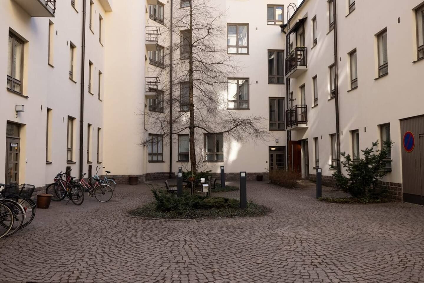 Un cortile con un albero, biciclette e un edificio con diverse finestre e balconi.