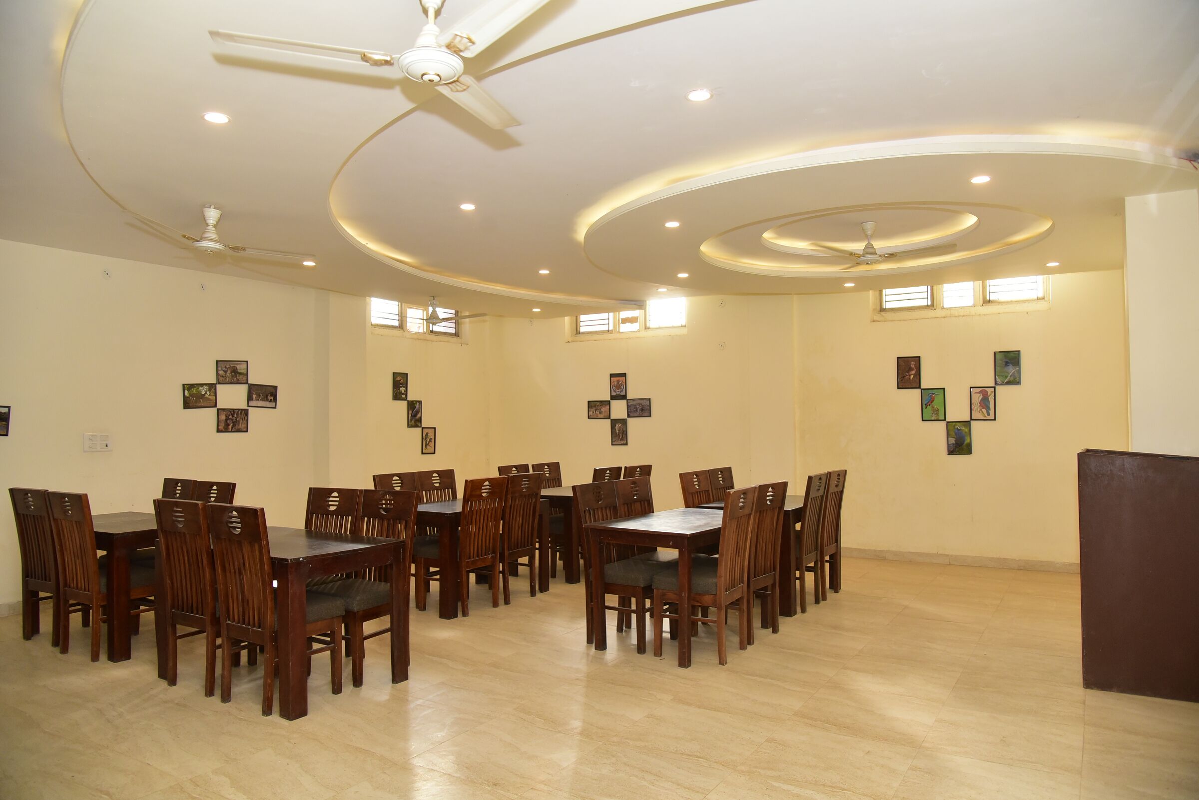 Un vaste espace dédié à la salle à manger, avec de nombreuses tables et chaises en bois, des ventilateurs de plafond et un éclairage encastré.