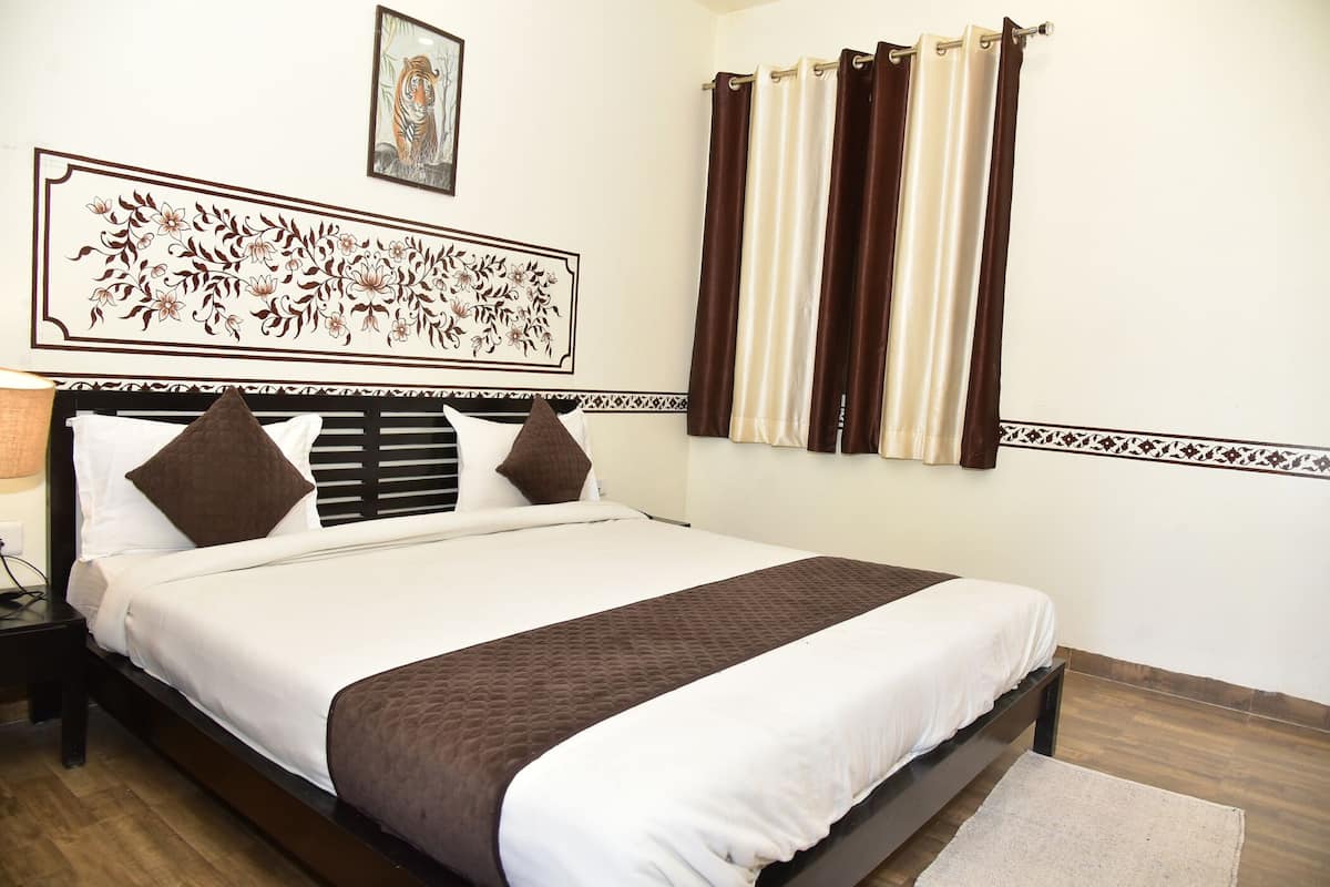 A neatly made bed with a brown and white bedspread, a headboard with a decorative panel, and a window with brown curtains.