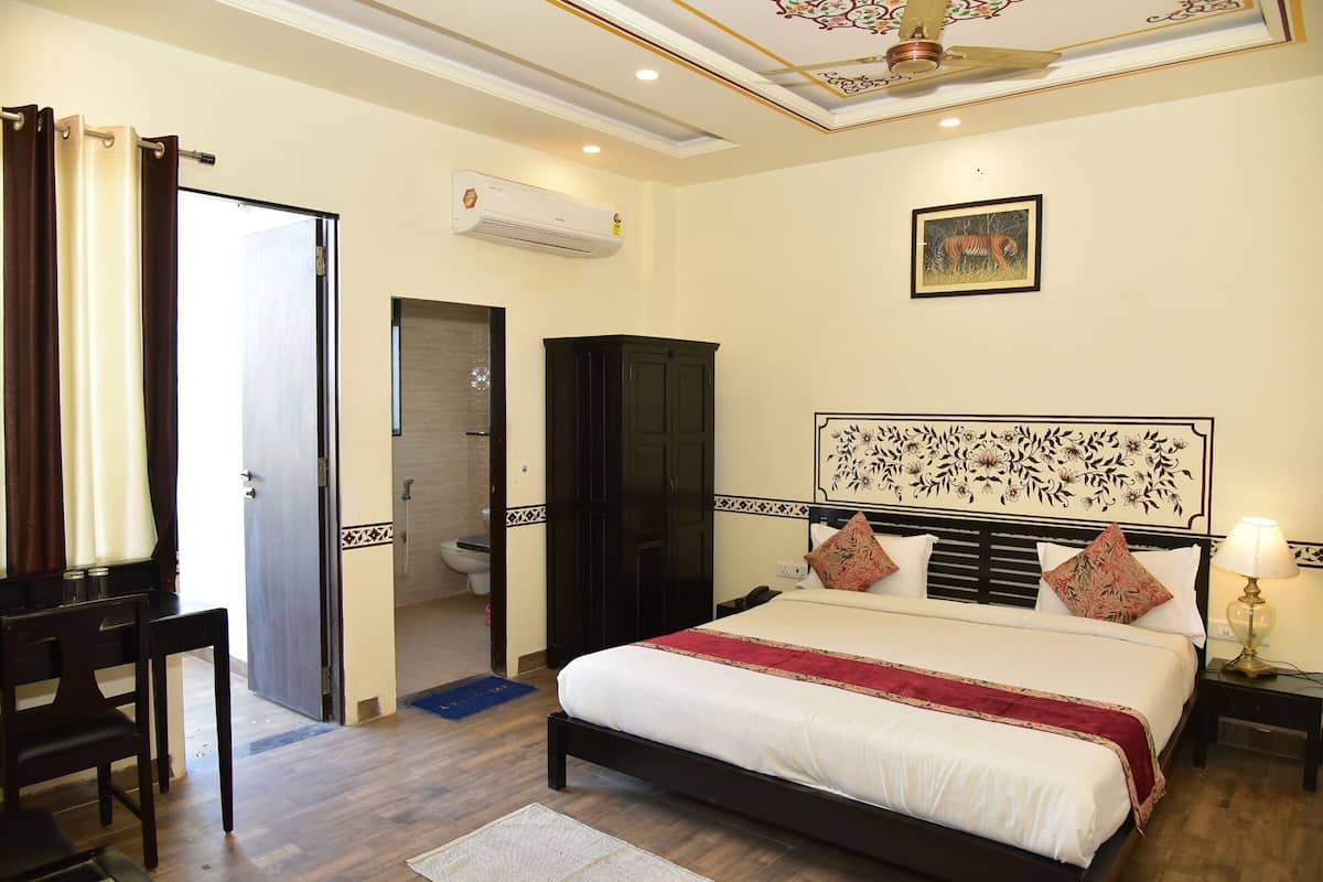A hotel room with a bed, a wardrobe, a desk, a chair, a bathroom, and a ceiling fan.