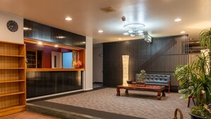 A modern lobby with a wooden bookshelf, a sofa, a coffee table, and a staircase. - Elan Hotel Lake Nojiri (Shinano)