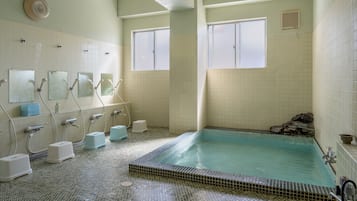 A bathroom with a large bathtub, multiple sinks, and a tiled floor.