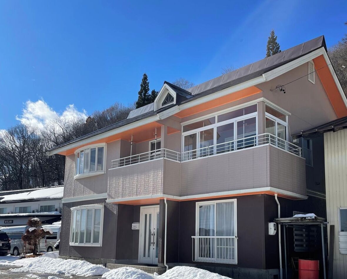 Un bâtiment à deux étages, doté d’un balcon à l’étage supérieur, d’une porte de garage et d’un sol recouvert de neige.