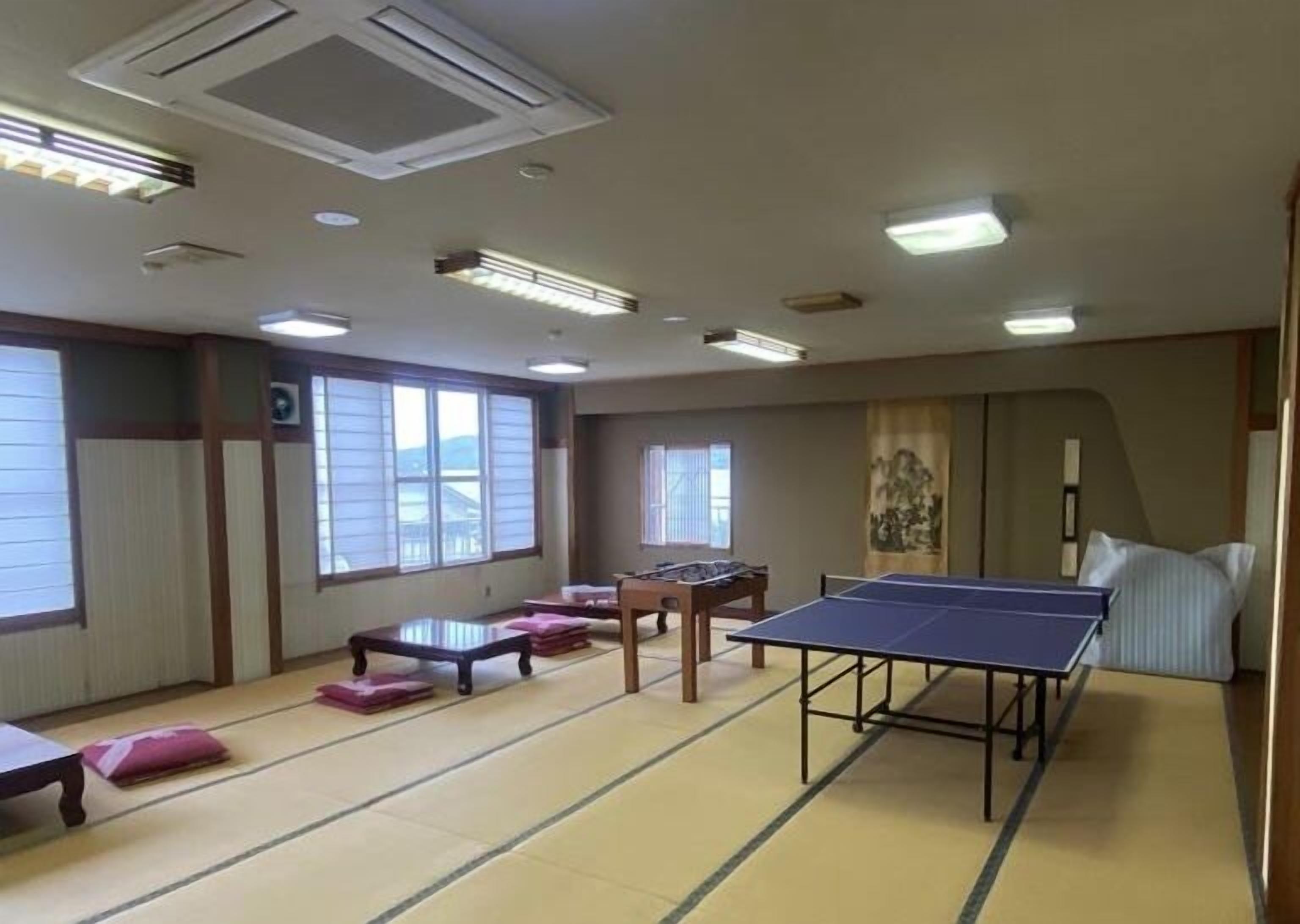 A tatami mat room with a ping pong table, a small table, and a futon bed.