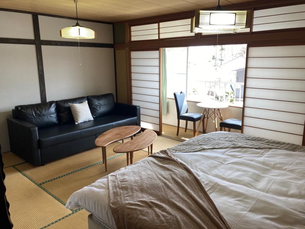 Een traditionele Japanse kamer met tatami vloeren, een laag bed, een bank en een kleine tafel.
