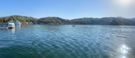 Un lago tranquilo con un bote amarrado a la izquierda, rodeado de colinas y cielos despejados.