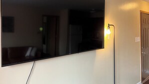 Un televisor de pantalla plana montado en la pared, con una lámpara a su lado.