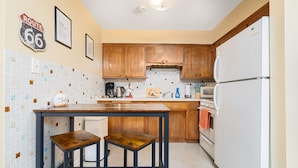 Una cocina con armarios de madera, un refrigerador blanco, una cafetera y un salpicadero de azulejos.