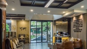 A modern reception area with a seating area, a reception desk, and a large window offering a view of the outdoors. - Le Bis Hotel  (Chiang Mai)