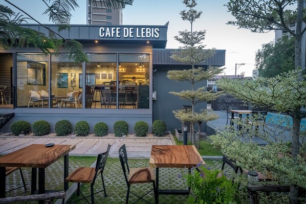 A modern cafe with outdoor seating and a well-maintained garden.