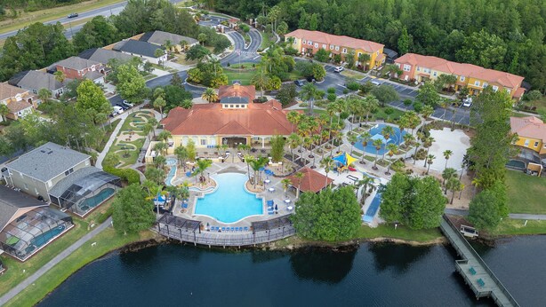 Oversigtsbillede af et resort med en central swimmingpool, forbundne bygninger og en dok over vandet.