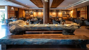 A modern restaurant with a central wooden table, seating around it, and a wooden ceiling. - Zone Niathu Dimapur By The Park (Dimapur)