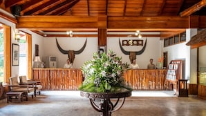 A lobby with a reception desk, wooden furniture, and a floral centerpiece. - Zone Niathu Dimapur By The Park (Dimapur)