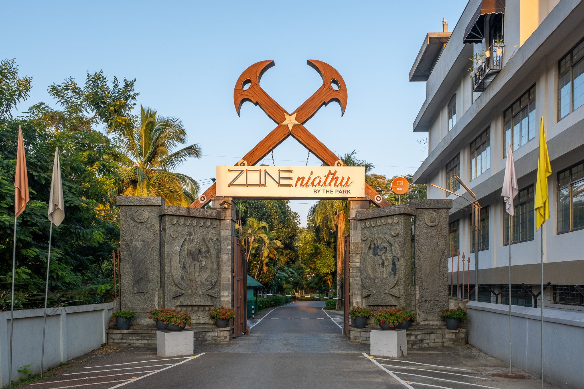 Entrada de un hotel con un letrero que dice “ZONE niathu by the park” y un arco de piedra.