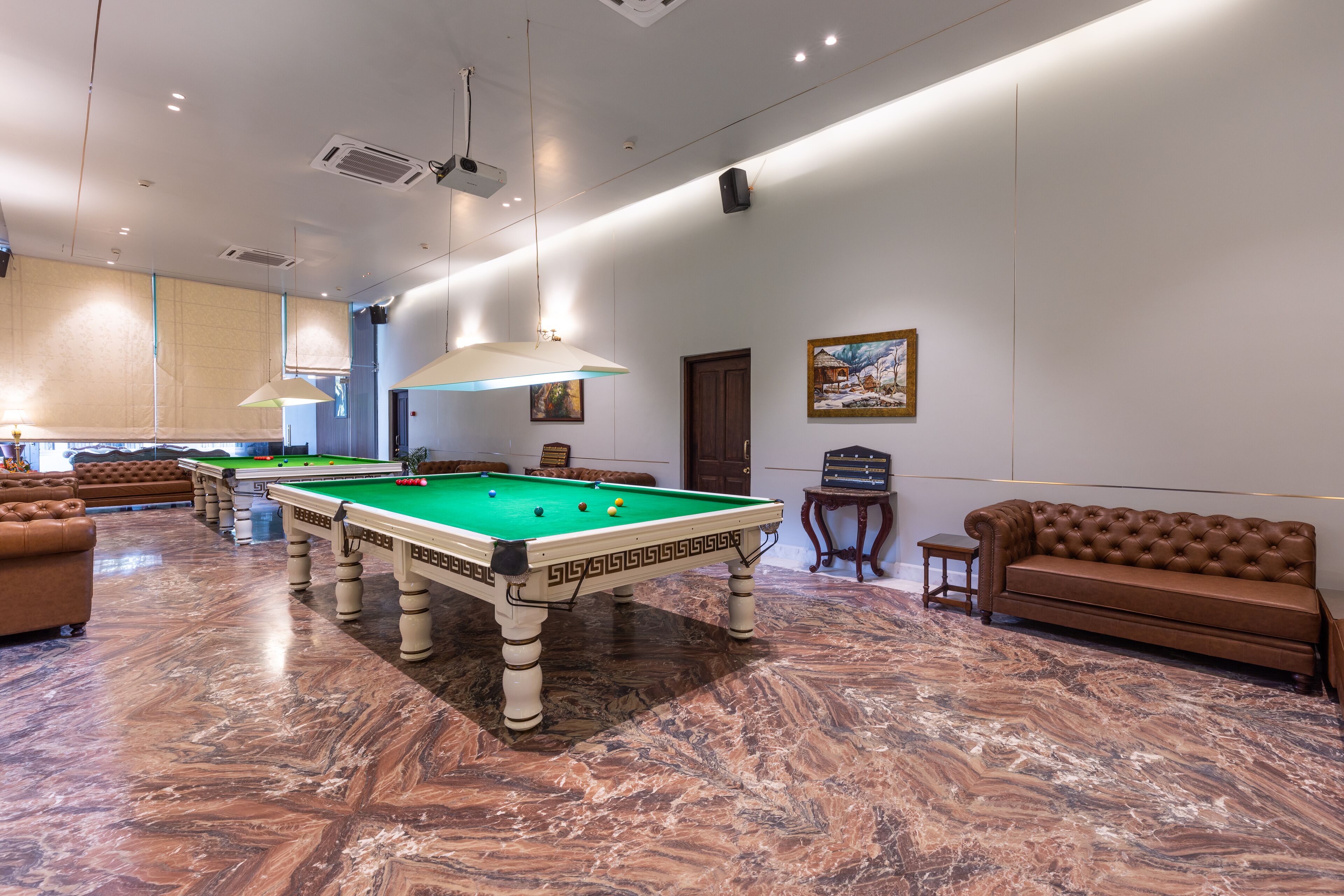 Une salle de billard équipée d’une table de billard, de canapés et d’un sol en marbre.