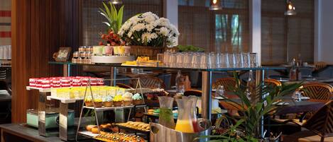 En buffet med forskellige retter, en blomsterdekoration og et kande med juice.
