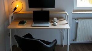 A modern workspace with a laptop, a smartphone, a cup of coffee, and a desk lamp.