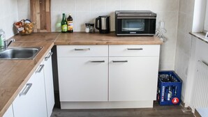 A modern kitchen with white cabinets, a wooden countertop, a built-in microwave, and a blue crate with bottles.