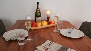 A dining table set with plates, cutlery, glasses, a bottle of champagne, and a candle.