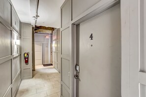 A hallway with a fire extinguisher, a door labeled '4', and a doormat at the entrance.