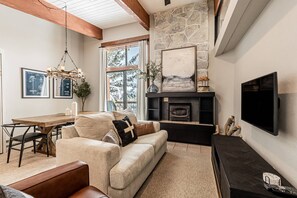 A cozy living room with a fireplace, a television, and a dining area with a table and chairs.