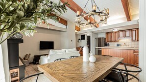 A spacious living area with a large wooden dining table, modern kitchen, and a unique antler chandelier.