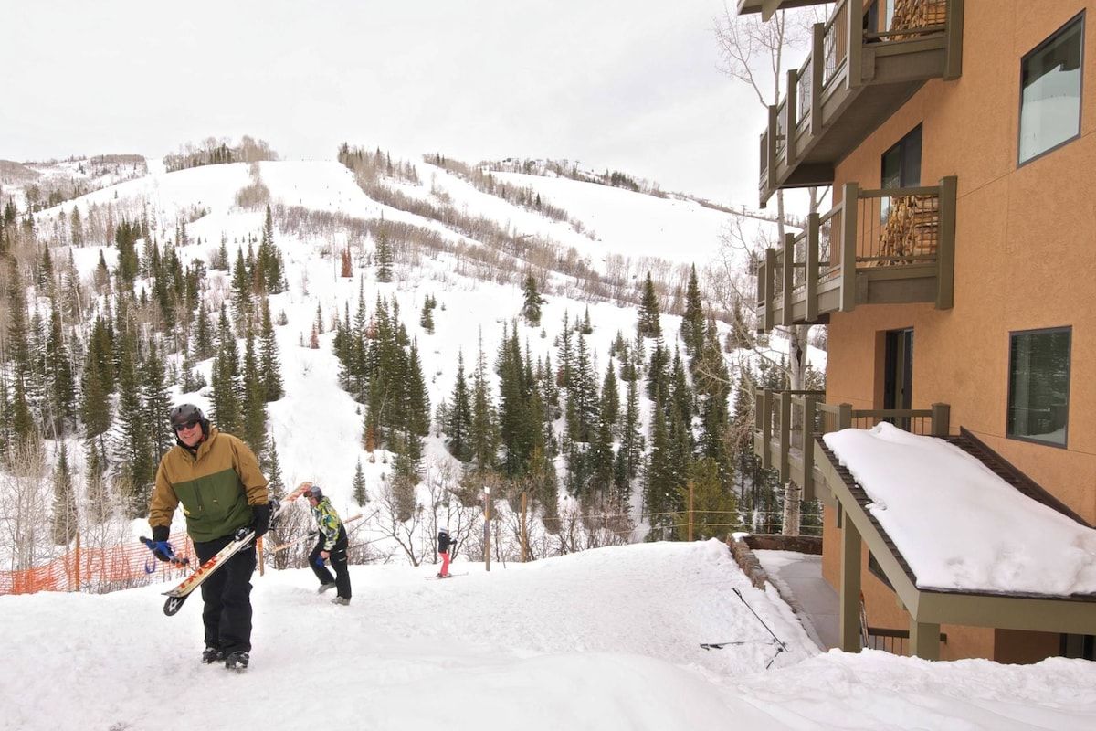 A building with a balcony and a ski slope in the background.