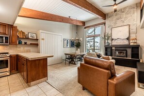 A kitchen with a central island, wooden cabinets, and a stone fireplace.