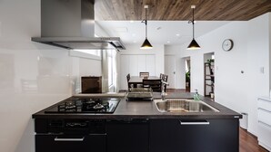 A modern kitchen with black appliances, a central island, and pendant lighting. - MARINUS (Miyakojima)