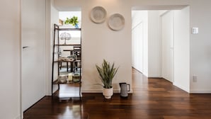 A hallway with wooden flooring, a potted plant, and two wall-mounted decorative plates. - MARINUS (Miyakojima)