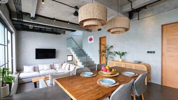 Un comedor moderno con una mesa de madera, sillas de mimbre y una gran planta como centro de mesa.