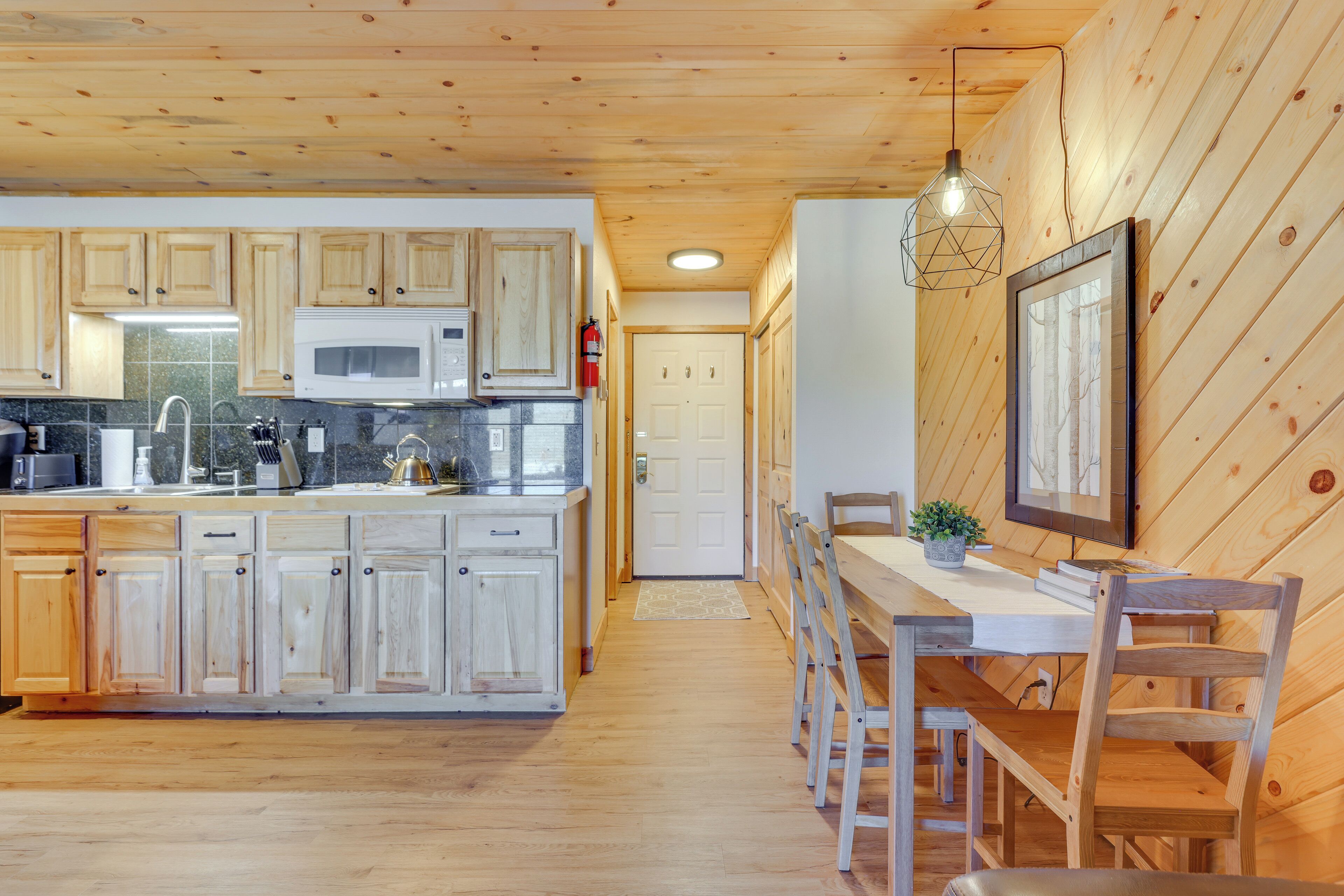 A kitchen with wooden cabinets, a microwave, and a dining area with a table and chairs.