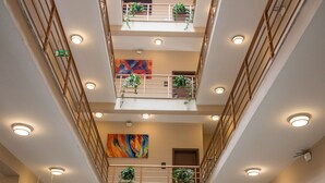A multi-level atrium with a central open space, railings, and ceiling lights. - South Gate Hotel Apartment (Addis Ababa)