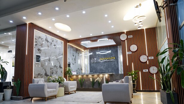 A modern hotel lobby with a reception desk, seating area, and decorative plants. - South Gate Hotel Apartment (Addis Ababa)
