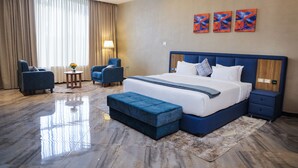 A modern hotel room with a large bed, two armchairs, a small table, and a decorative lamp. - South Gate Hotel Apartment (Addis Ababa)