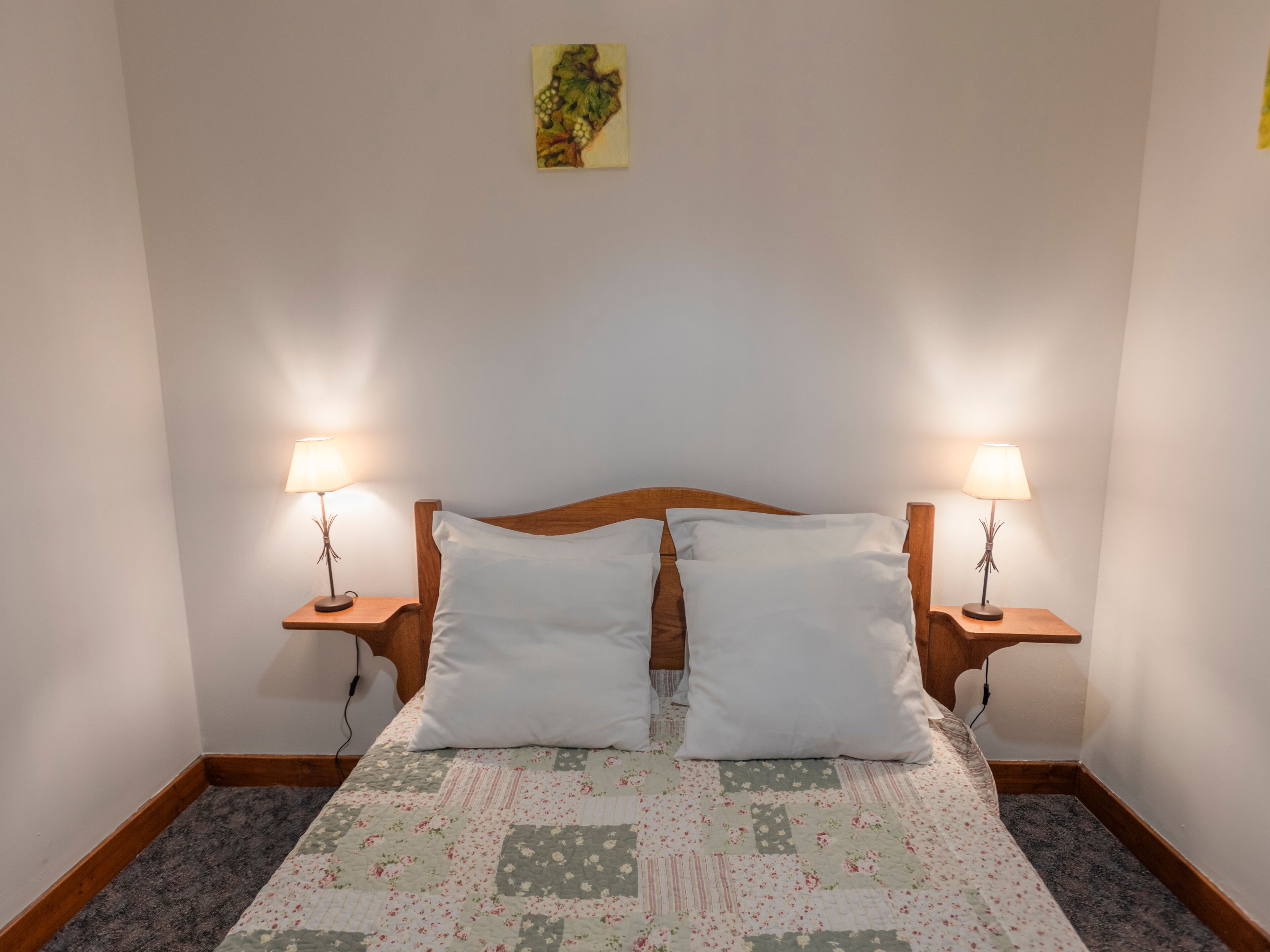 Une chambre à coucher avec une tête de lit en bois, deux lampes de chevet et une couvre-lit à motifs floraux.