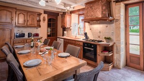 A rustic kitchen with wooden cabinets, a dining table set for four, and a built-in oven.