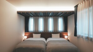 Una habitación de hotel con dos camas, un cabecero de madera y una ventana con cortinas.