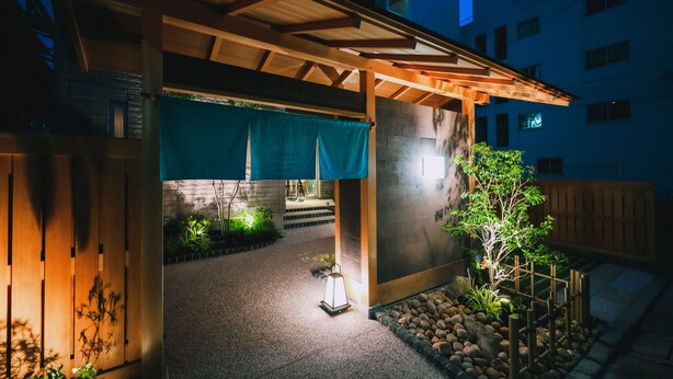 Un espacio al aire libre cubierto con un porche de madera, un farol y un pequeño árbol.