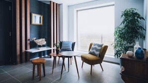 Una sala de estar moderna con sofá, sillón, mesa de centro y una planta en maceta.