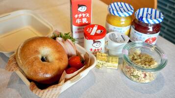 A meal with a bagel, cherry tomatoes, and condiments on a table.