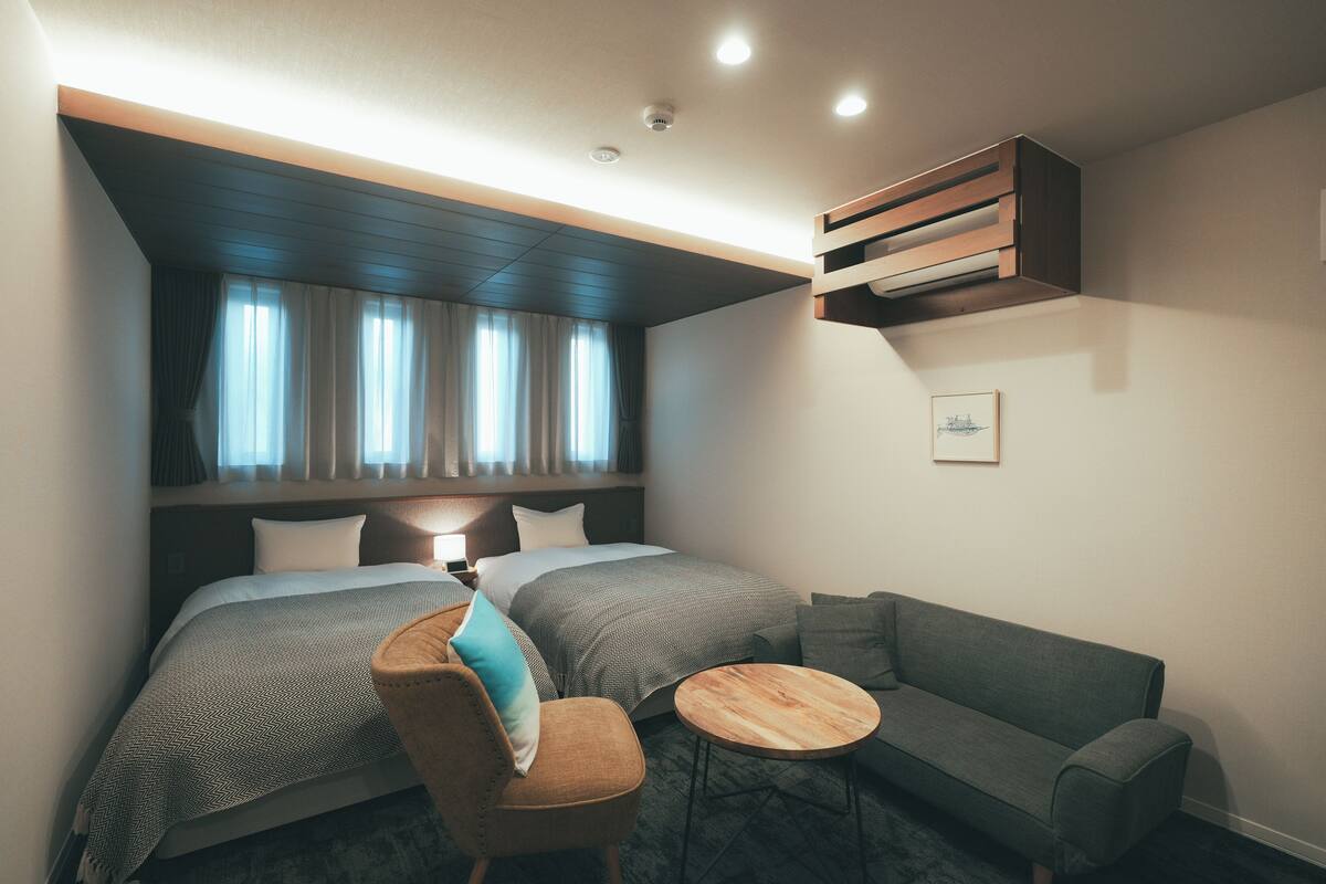 Een moderne hotelkamer met een groot bed, twee nachtkastjes, een sofa en een klein rond tafeltje.