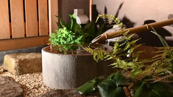 A stone basin with water and plants, surrounded by rocks and pebbles.