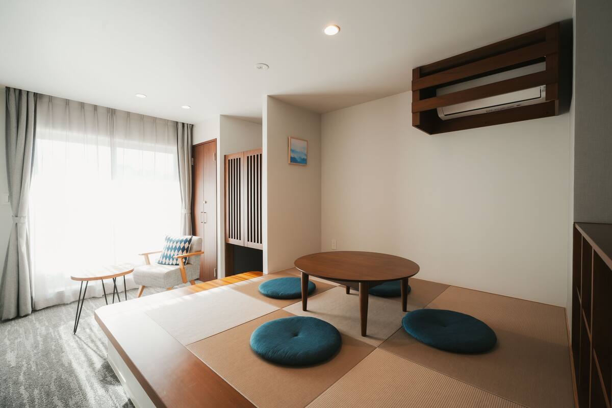 Een moderne hotelkamer met tatami matten, een ronde tafel en een traditionele Japanse schuifdeur.