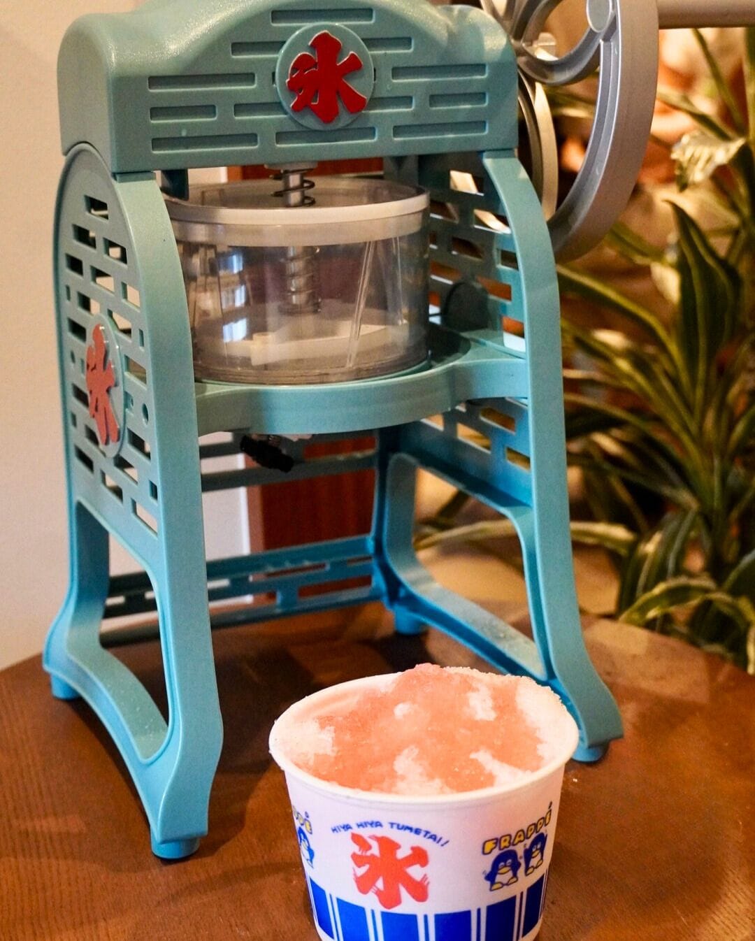 A blue portable coffee maker with a clear water container and a cup of coffee.