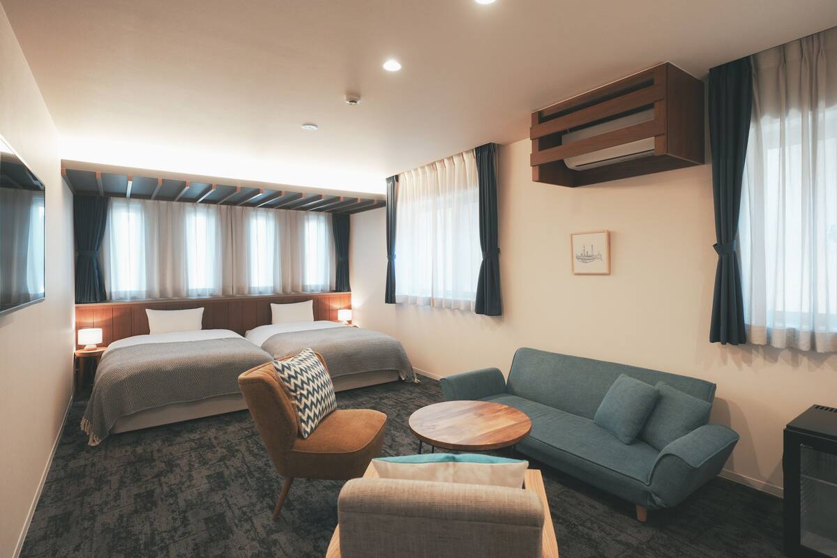Een hotelkamer met een groot bed, twee nachtkastjes, een bank, een ronde salontafel en een televisie.