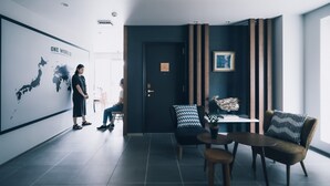 Un moderno vestíbulo de hotel con un mural de mapa mundial, una recepción y una zona de estar con cojines estampados.