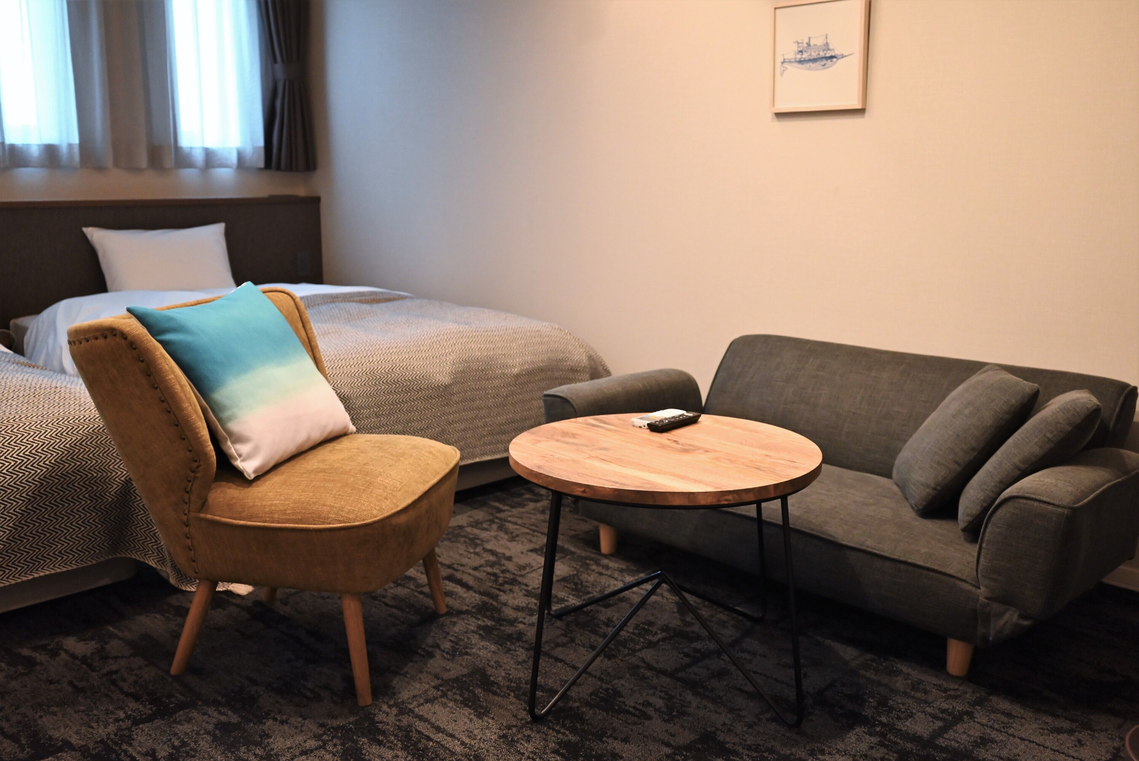 A hotel room with a bed, a sofa, a chair, and a small table.