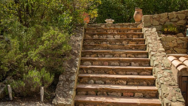 Eine Steintreppe mit rustikalem Design, die zu einer Tür mit einem Ziegeldach führt.